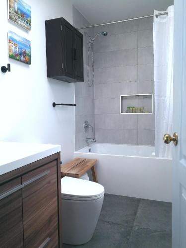 a bathroom with a tub and a toilet and a sink at Marpole Guest House in Vancouver