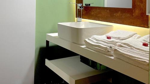 ein Badezimmer mit einem Waschbecken und Handtüchern auf einem Regal in der Unterkunft La Maison de Fuecopared in Florenz