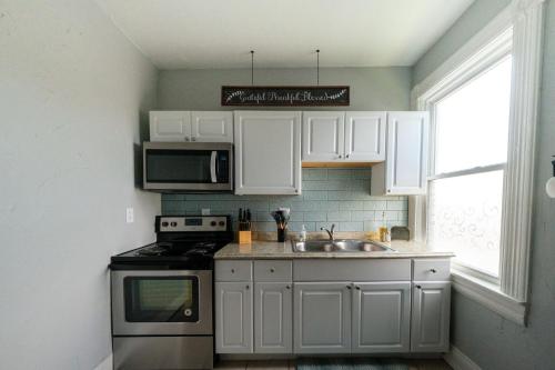 a kitchen with white cabinets and a sink and a stove at Robin's Nest - Miami U, Weddings or Spooky Nook! in Hamilton