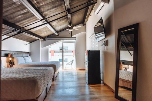 Cette chambre comprend 2 lits et un miroir. dans l'établissement Loft Hotel Malecón Vallarta, à Puerto Vallarta