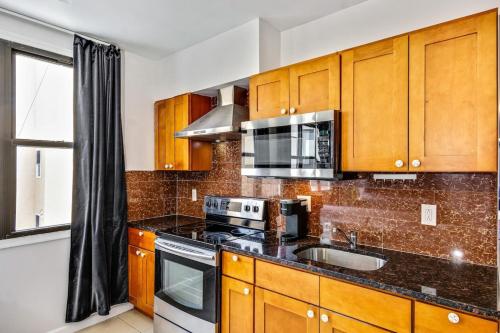 uma cozinha com armários de madeira, um lavatório e um micro-ondas em Classic Modern with a splash of Glam 2BD Apt em Filadélfia