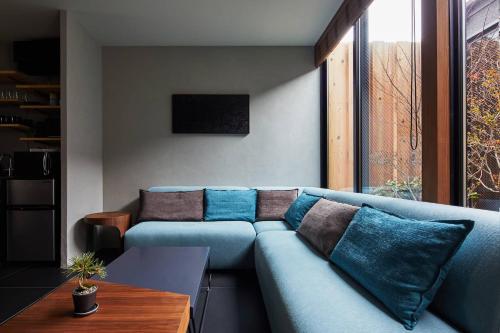a living room with a blue couch with pillows at HANARE KYOTO Hachijoguchi in Kyoto