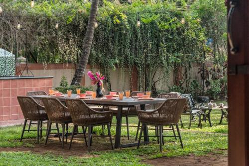 an outdoor table with chairs and a table with flowers on it at Saffronstays Casa Del Palms, Alibaug - luxury pool villa with chic interiors, alfresco dining and island bar in Alibaug