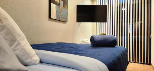 a white bed with a blue comforter on top of it at Hostal GGG in Ensenada