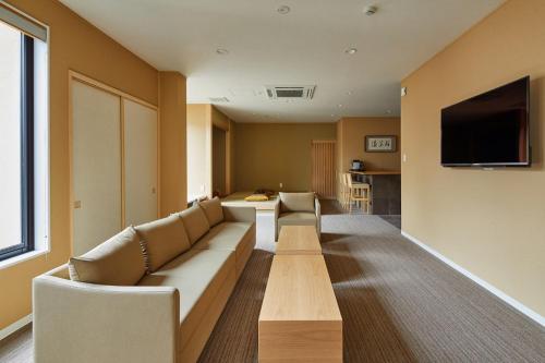 ein Wohnzimmer mit einem Sofa und einem Flachbild-TV in der Unterkunft Onsen no yado Gion Maisen Bettei by YADORU KYOTO HANARE in Kyoto