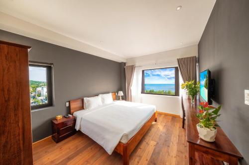 a bedroom with a white bed and two windows at Gaia Hotel Phu Quoc in Phu Quoc