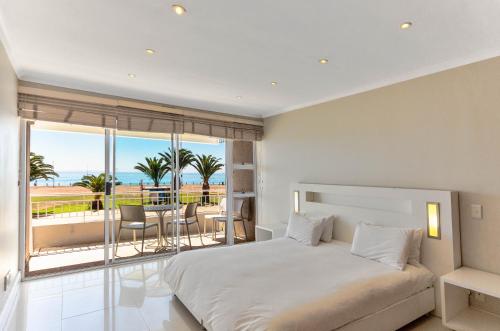 a bedroom with a bed and a balcony with palm trees at First floor with beautiful sea view in Cape Town