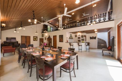 a dining room with a long table and chairs at Saffronstays Casa Del Palms, Alibaug - luxury pool villa with chic interiors, alfresco dining and island bar in Alibaug