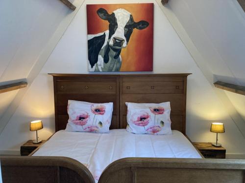 a bedroom with a bed with a cow painting on the wall at Tiny House Holland in Oudesluis