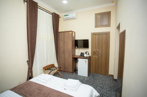 a hotel room with a bed and a desk at Rayyan Hotel Samarkand in Samarkand