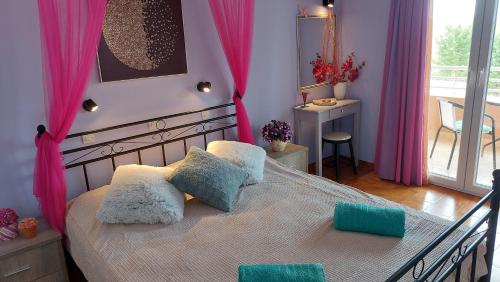 una camera da letto con un letto con cuscini rosa e blu di Sausan Hotel a Sidari