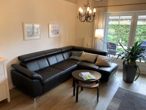 a living room with a black leather couch and a table at Huus Utspann in Nordstrand