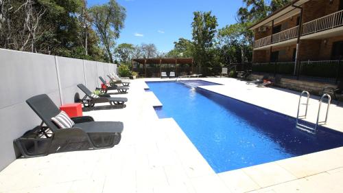 Una piscina con tumbonas al lado de un edificio. en Hawks Nest Motel, en Hawks Nest