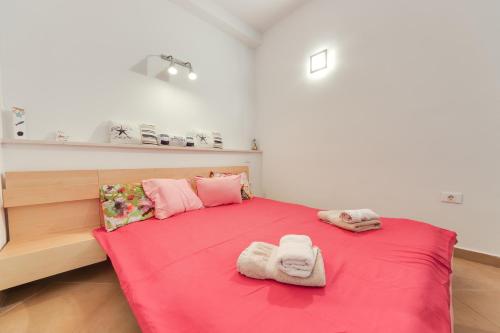 ein Schlafzimmer mit einem roten Bett mit zwei Handtüchern darauf in der Unterkunft Piran Punta Beach Apartment in Piran