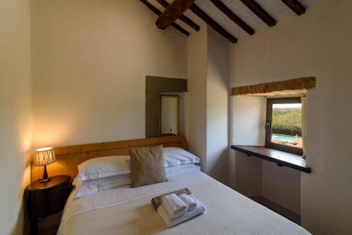 a bedroom with a white bed with a window at Monastero San Silvestro in Cortona