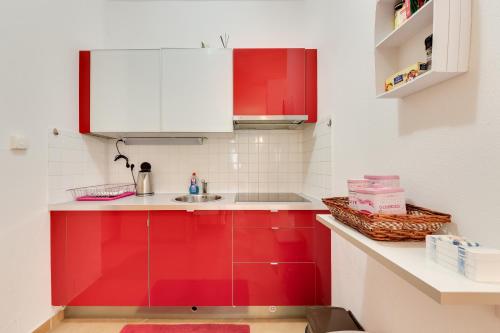 a kitchen with red cabinets and a sink at Piran Punta Beach Apartment in Piran