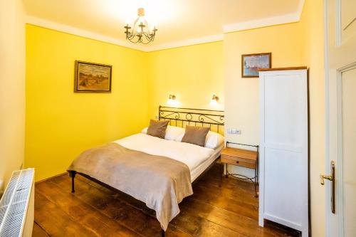a bedroom with a bed with yellow walls and a desk at Penzion Thallerův Dům in Český Krumlov