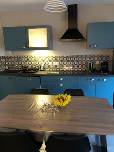 une cuisine avec une table en bois et des fleurs jaunes. dans l'établissement Gerardmer : Residence 