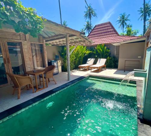 a swimming pool with a table and chairs next to a house at GiliZen Resort - Private Pool Villas in Gili Islands