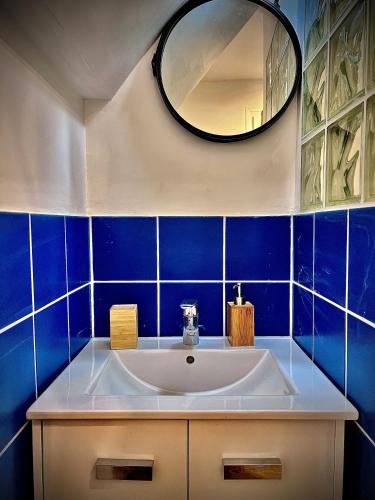 La salle de bains est pourvue de carrelage bleu, d'un lavabo et d'un miroir. dans l'établissement Appartement mezzanine/jardin/terrasse village naturiste, au Cap d'Agde
