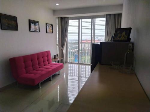 a living room with a red couch and a sliding glass door at Lovely 2 bed-room Menara U Shah Alam near MSU in Shah Alam