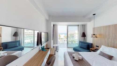 a bedroom with two beds and two blue chairs at The Blue Ivy Hotel & Suites in Protaras