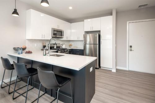 a kitchen with white cabinets and a kitchen island with stools at Luxury Apartments by Hyatus at Pierpont in New Haven