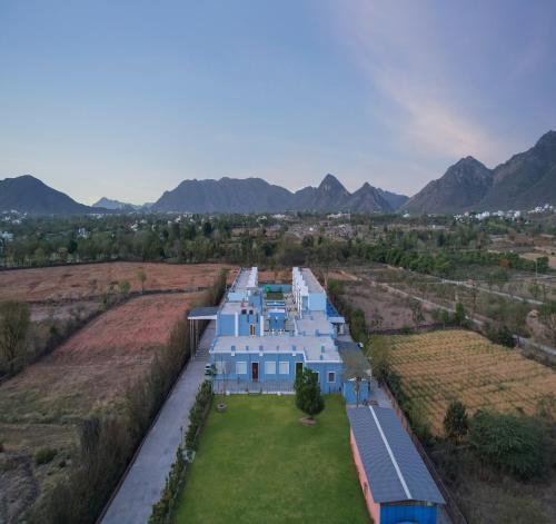 an aerial view of a blue house with mountains in the background at Red Tullip MD Valley Resort and Spa in Udaipur