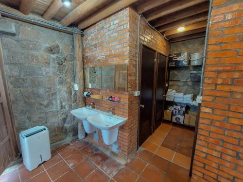 a bathroom with a sink and a brick wall at 芹聚輕旅 Qinju Light Hostel in Beigan