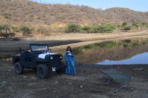 a woman is standing next to a jeep at Red Tullip MD Valley Resort and Spa in Udaipur