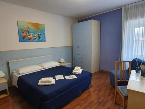 a bedroom with a blue bed and a table and chair at Hotel La Bussola in Muggia