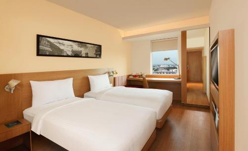 a hotel room with two beds and a window at ibis Coimbatore City Centre - An Accor Brand in Coimbatore