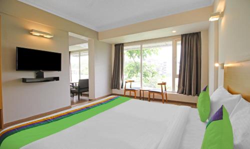 a hotel room with a large bed and a flat screen tv at Treebo Grand Legacy Shahenshah in Dehradun