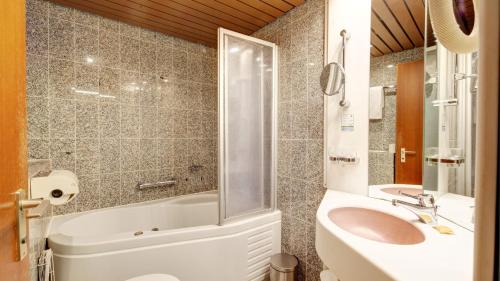 a bathroom with a sink and a toilet and a tub at Hotel Spahr in Stuttgart