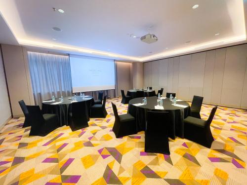 a conference room with tables and chairs and a projection screen at Mercure Kuala Lumpur Glenmarie in Shah Alam
