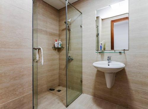 ein Bad mit einem Waschbecken und einer Glasdusche in der Unterkunft *Ha Long Homestay @ Sunrise Apartment- 4 BR in Hạ Long