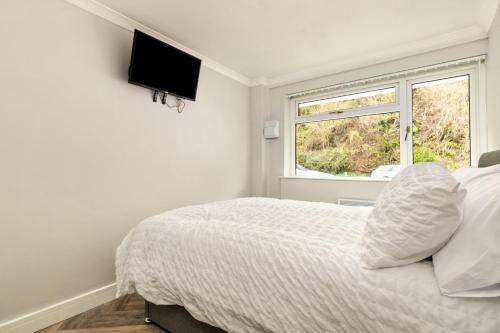 Un dormitorio blanco con una cama y una ventana. en Pleasant View - Direct Beach Access, Sea Views and Parking, en Saundersfoot