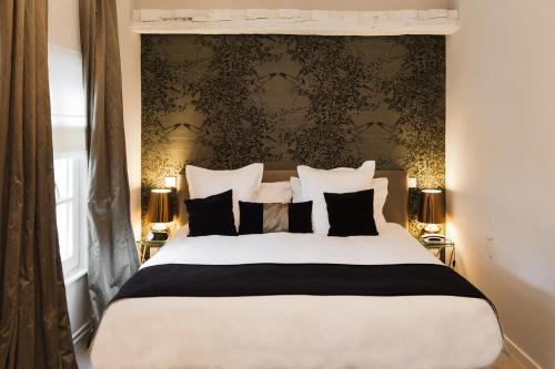 a bedroom with a large bed with black and white pillows at Clarance Hotel Lille in Lille