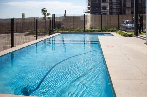 una piscina de agua azul frente a una valla en Fumo House Lifestyle Apartments, en Midrand