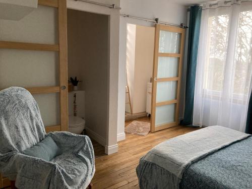 um quarto com uma cama, uma cadeira e uma janela em chambre zen château de la Bouchatte em Chazemais