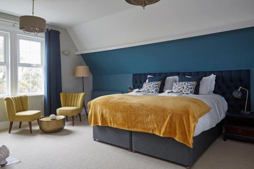 a blue bedroom with a bed and two chairs at Sentry Mead Hotel in Totland