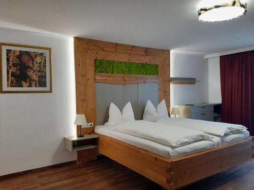 Schlafzimmer mit einem großen Bett mit einem Kopfteil aus Holz in der Unterkunft Gasthofladen Schneeweiss in Attersee am Attersee