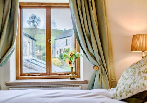 a bedroom with a window with a vase of flowers at Red Lion House in Hartington