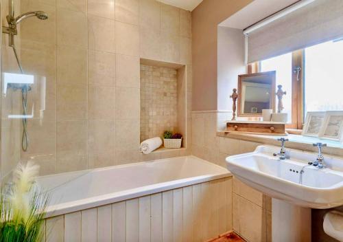 a bathroom with a bath tub and a sink at Red Lion House in Hartington