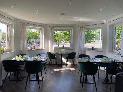 a dining room with tables and chairs and windows at Hotel zum See garni in Dießen am Ammersee