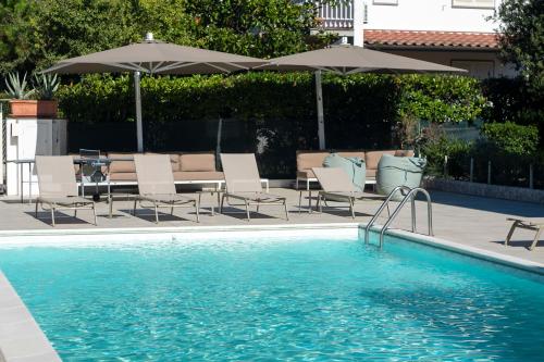 a swimming pool with chairs and umbrellas at Hotel Tarabella in Forte dei Marmi