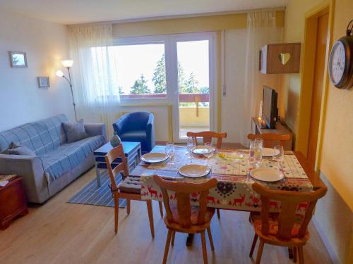 ein Wohnzimmer mit einem Tisch mit Stühlen und einem Sofa in der Unterkunft Apartment Imperia by Interhome in Crans-Montana