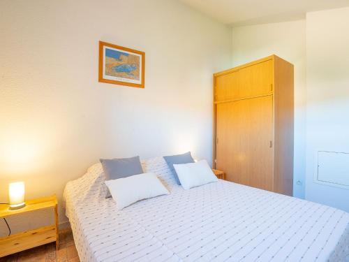 une chambre avec un lit blanc et une armoire en bois dans l'établissement Holiday Home Les Marines du Roussillon-2 by Interhome, à Saint Cyprien Plage