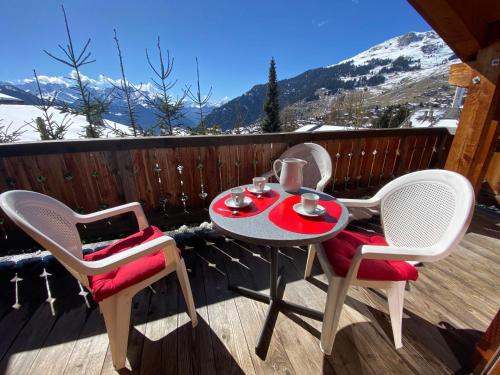 un tavolo e due sedie su una terrazza con montagne innevate di Apartment Boule de Neige by Interhome a Verbier