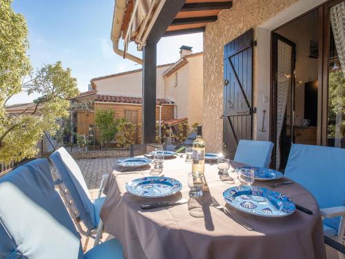 a table with blue and white plates and glasses at Holiday Home Le Hameau des Bougainvilliers by Interhome in Saint-Cyprien-Plage